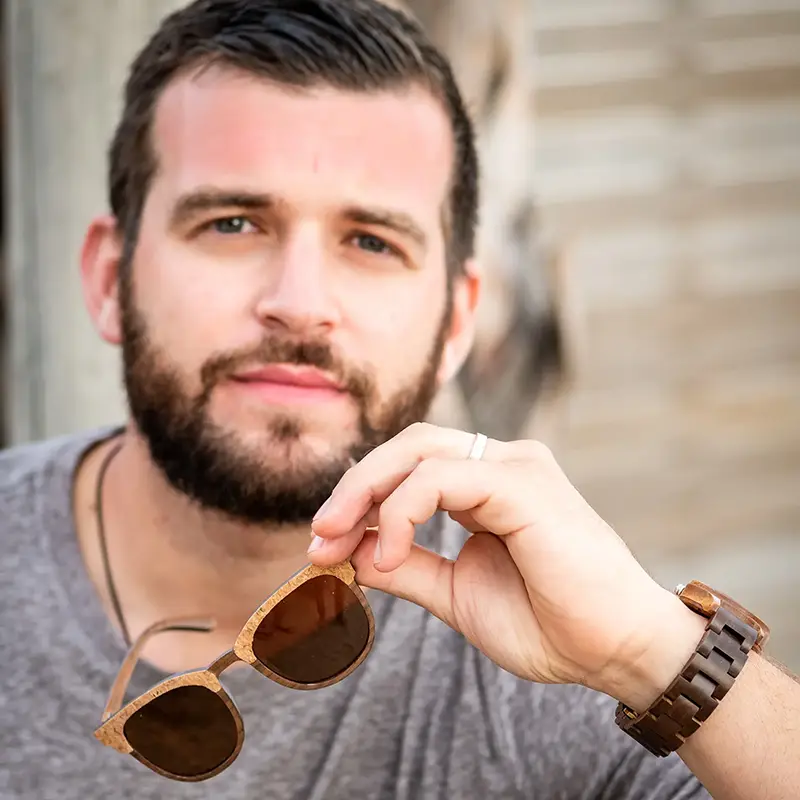 Un modèle portant les lunettes Classic R15 dans un jardin ensoleillé, mettant en valeur un design Clubmaster élégant.