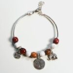 Bracelet jonc en bois Howlite Samia exposé sur un fond blanc, mettant en évidence ses perles naturelles et ses breloques argentées.