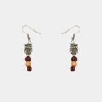 Une paire de boucles d’oreilles pendantes avec une chouette filigrane en argent et des perles de bois précieux.