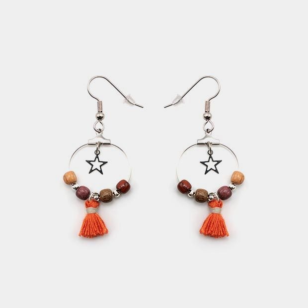 Boucles d’oreilles en bois précieux avec étoile filigrane argentée, sur fond blanc.