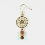 Vue rapprochée des boucles d'oreilles en bois Paola avec un motif étoile dorée.