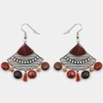 Boucles d'oreilles en bois multicolore avec détails filigranés argentés et pompons.