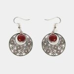 Gros plan sur une paire de boucles d'oreilles multicolores Noélie avec un design créole et des perles en bois précieux.