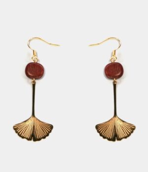 Femme portant les boucles d’oreilles Nancy en feuille ginkgo amarante