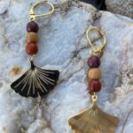 Boucles d'oreilles en bois avec trois perles multicolores et une feuille de ginkgo dorée.