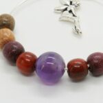 Gros plan sur des boucles d’oreilles légères aux tons naturels, alliant des perles multicolores et une pierre d’améthyste.