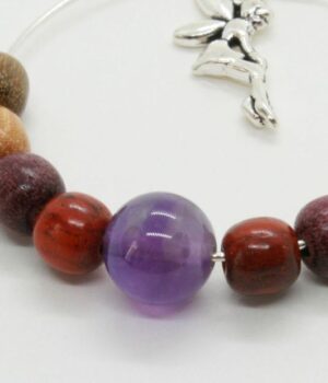 Gros plan sur des boucles d’oreilles légères aux tons naturels, alliant des perles multicolores et une pierre d’améthyste.