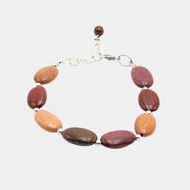 Bracelet en bois multicolore Tea posé sur fond gris, mettant en valeur les perles artisanales en forme ovales.