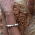 bracelet Alenzo enveloppé autour d'un poignet féminin, mettant en valeur le mélange des pierres howlite et des perles en bois d'acajou.