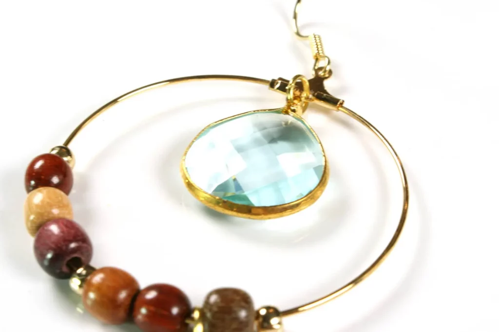 Boucles d'oreilles créoles en bois multicolore avec pierre de calcédoine bleu clair et étoile dorée.