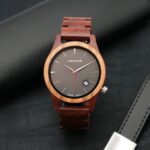 Une montre en bois pour homme avec un boîtier bicolore en noyer et palissandre, cadran sport et aiguilles rouges.