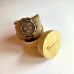 Coffret en noyer everest My Essenciel contenant une montre en bois chronographe posée sur son coussin en toile naturelle, avec maillons supplémentaires.