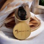 Coffret en bambou collection Métro7 My Essenciel contenant une montre en bois d'ébène homme posée sur son coussin en toile naturelle, avec maillons supplémentaires.