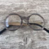 Lunettes en bois Océania posées sur une table, montrant leur design écoresponsable et forme ronde classique.