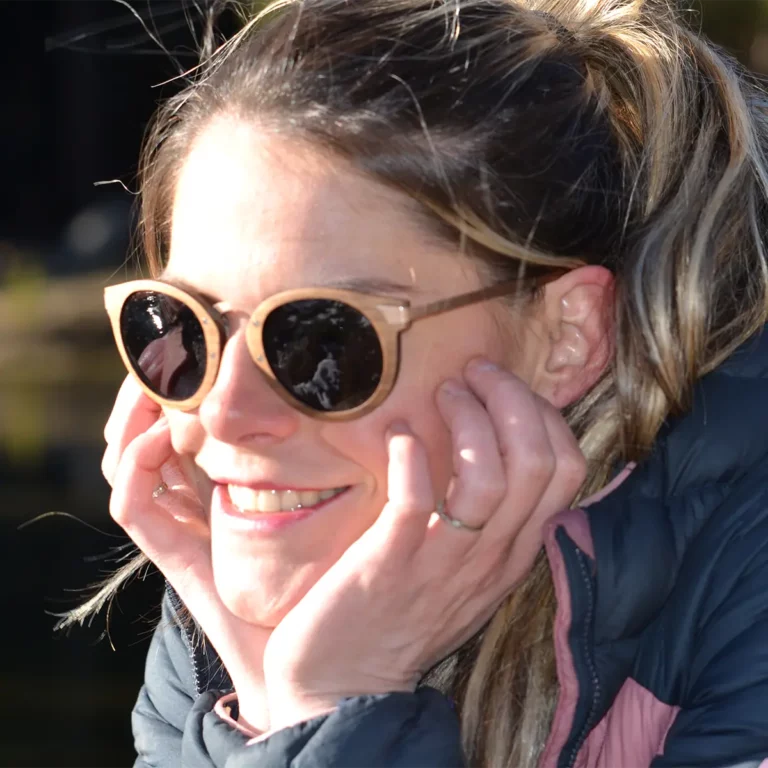 Lunettes de soleil Élizabeth en bois naturel, posées dans leur étui raffiné en liège, entourées d’accessoires minimalistes.