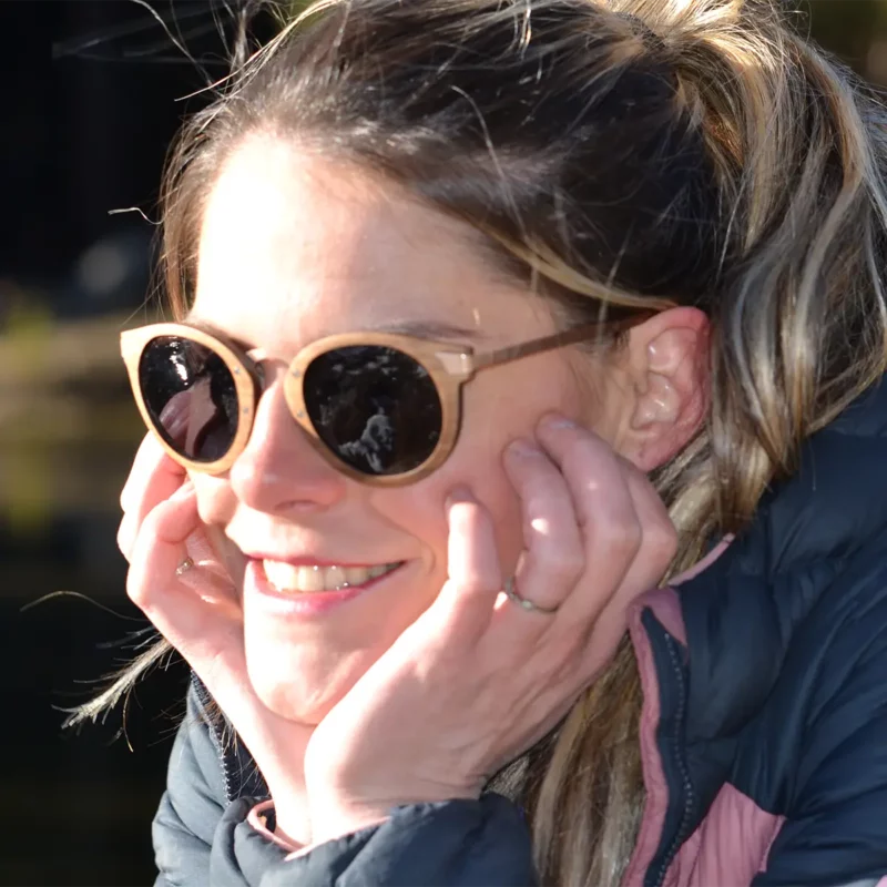 Lunettes de soleil Élizabeth en bois naturel, posées dans leur étui raffiné en liège, entourées d’accessoires minimalistes.