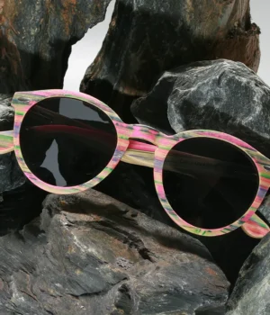 Lunettes en bois Spector multicolore posées sur une table en lumière naturelle, fabriquées à partir de skateboards recyclés, avec verres polarisés UVA400.