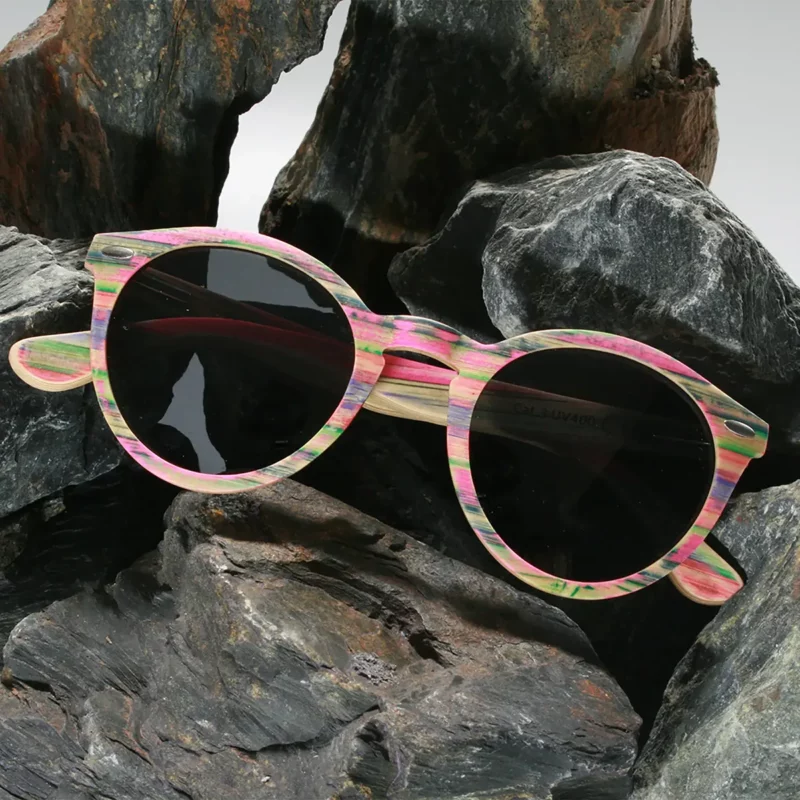 Lunettes en bois Spector multicolore posées sur une table en lumière naturelle, fabriquées à partir de skateboards recyclés, avec verres polarisés UVA400.