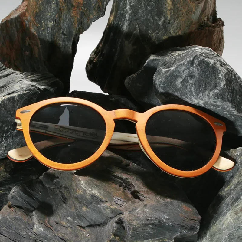 Lunettes de soleil Spector Orange en bois recyclé avec un design multicolore, posées sur une surface marbrée.