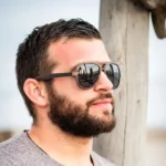 Lunettes Mac-Arthur bicolore en bois d’ébène avec monture Wayfarer, posées sur un étui en liège naturel.