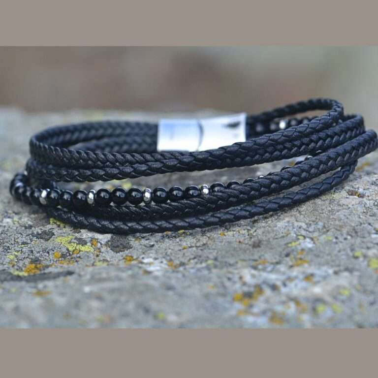 Bracelet multi-rangs en cuir noir tressé avec pierres naturelles en onyx, posé sur un socle en pierres.