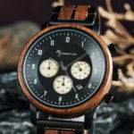 Gros plan sur le cadran de la montre chronographe en bois noir Nomadis avec trois sous-cadrans beige métallisé.