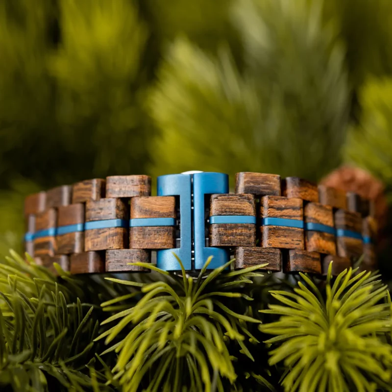 Bracelet réglable en bois de noyer renforcé d’une bande métallique bleue.