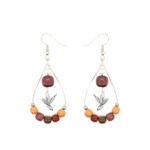 Un zoom artistique sur les boucles d'oreilles bois colibri Serrenna, illustrant le savoir-faire artisanal et les matières d'exception.