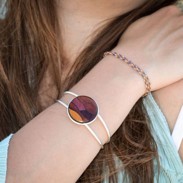 Gros plan sur le médaillon rond de 25 mm en marqueterie du bracelet multicolore Fany, conçu à partir d'essences de bois rares comme l'amarante et le palissandre.