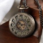 Montre à gousset Tomy en laiton verdâtre posée sur une table en bois, mettant en avant ses détails raffinés.