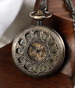 Montre à gousset Tomy en laiton verdâtre posée sur une table en bois, mettant en avant ses détails raffinés.