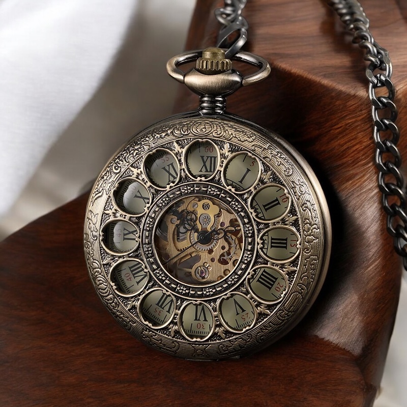 Montre à gousset Tomy en laiton verdâtre posée sur une table en bois, mettant en avant ses détails raffinés.