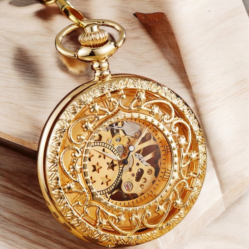 Présentation complète de la montre Stella Or avec cadran étoilé sur fond noir, chaîne en laiton et détails soignés.